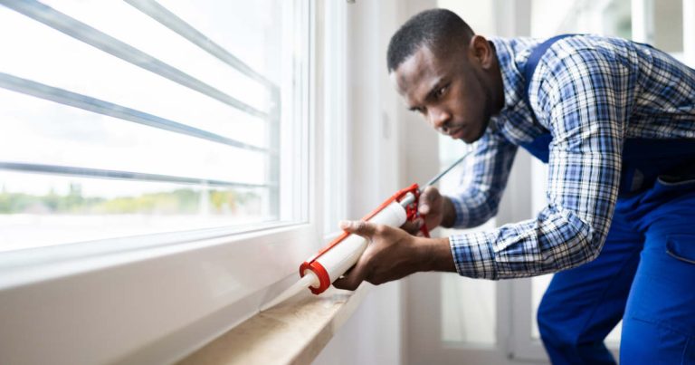 man caulking his window